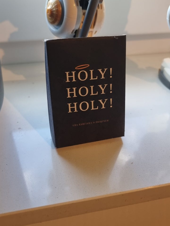 Czarne pudełko z napisem HOLY! HOLY! HOLY! stojące na parapecie, za nim robot z klocków